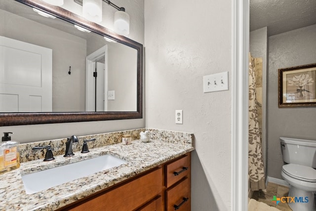 bathroom featuring tile patterned flooring, vanity, toilet, and walk in shower