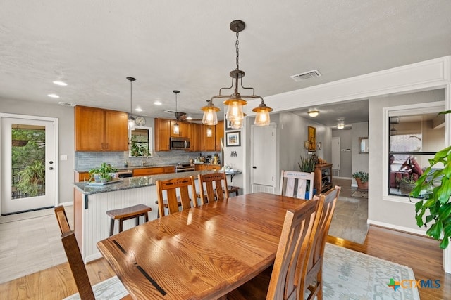 dining area featuring sink, a chandelier, a textured ceiling, and light wood-type flooring