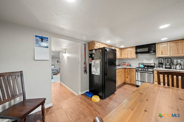 kitchen with black refrigerator, light brown cabinets, light hardwood / wood-style floors, and stainless steel range