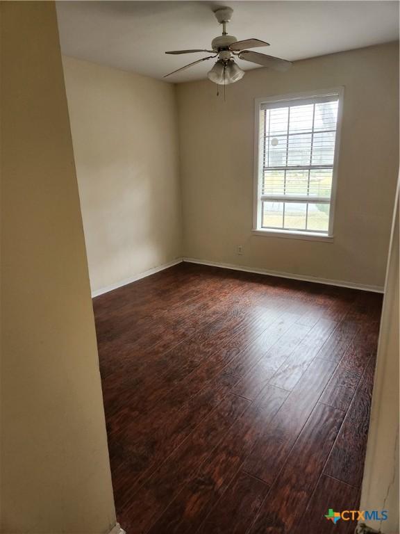 empty room with ceiling fan and dark wood-type flooring