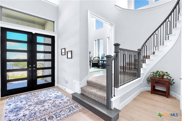 entryway featuring a high ceiling, french doors, and light hardwood / wood-style flooring