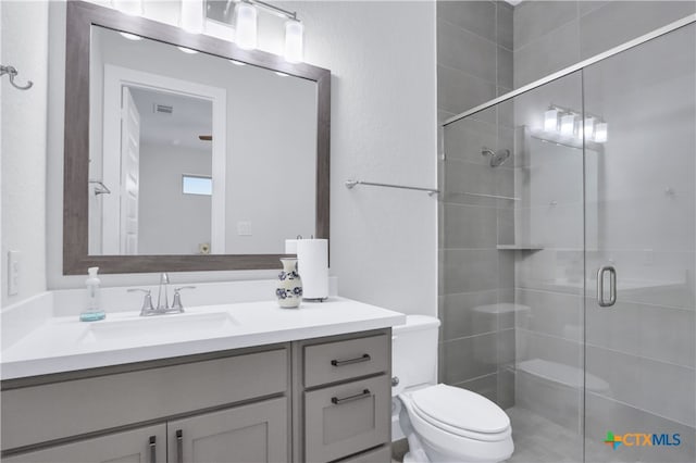 bathroom featuring vanity, a shower with door, and toilet