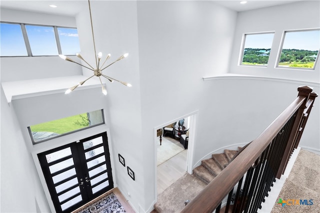 stairway with hardwood / wood-style flooring, a wealth of natural light, a chandelier, and french doors