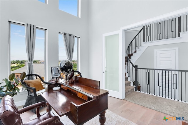 office space with a towering ceiling, a wealth of natural light, and light hardwood / wood-style flooring