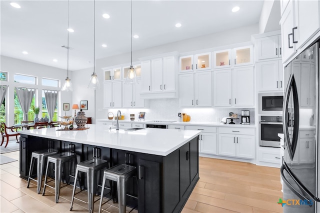 kitchen with white cabinetry, stainless steel appliances, an island with sink, and pendant lighting