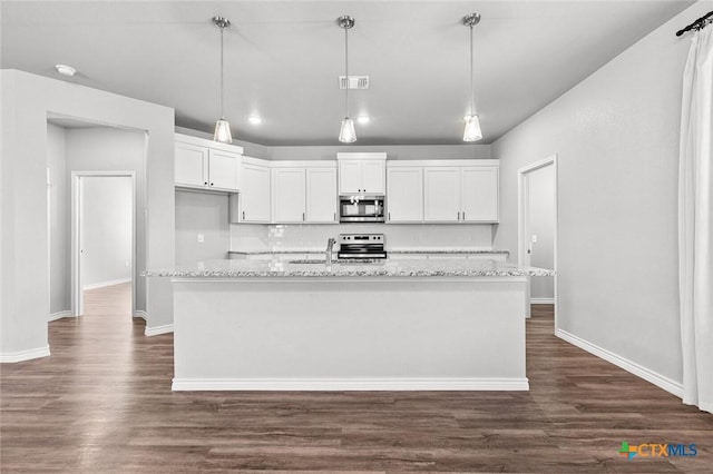 7917 Purvis St, Temple, TX 76502 - kitchen featuring appliances with stainless steel finishes, white cabinetry, dark wood-type flooring, light stone counters, and a center island with sink