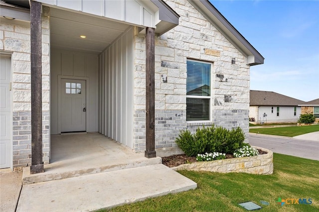 7917 Purvis St, Temple, TX 76502 - view of exterior entry with board and batten siding, stone siding, and a lawn