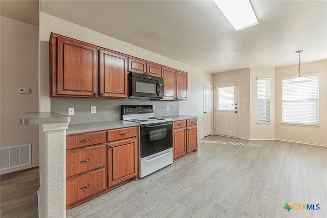 kitchen with range with electric stovetop, decorative light fixtures, a textured ceiling, and light wood-type flooring