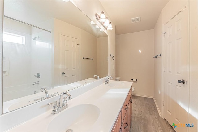 full bathroom featuring wood-type flooring, shower / washtub combination, vanity, and toilet