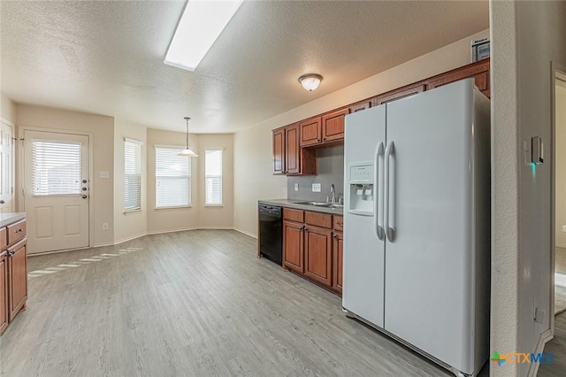 kitchen with sink, hanging light fixtures, black dishwasher, white refrigerator with ice dispenser, and light hardwood / wood-style floors