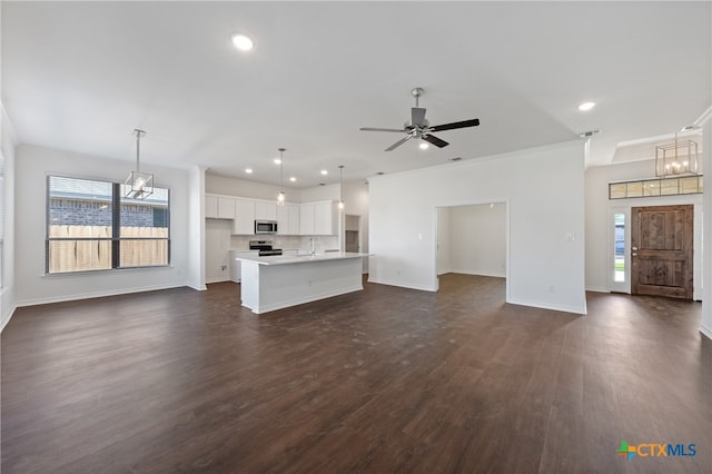 unfurnished living room featuring plenty of natural light, dark hardwood / wood-style flooring, ceiling fan with notable chandelier, and crown molding