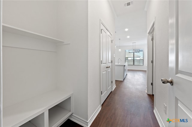 corridor featuring dark hardwood / wood-style floors, sink, crown molding, and a chandelier