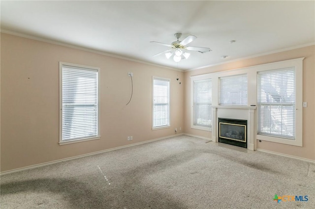 unfurnished living room with a fireplace with flush hearth, ornamental molding, carpet, baseboards, and ceiling fan