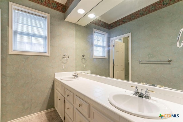 full bath featuring double vanity, baseboards, and a sink