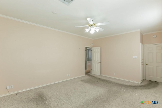 spare room with a ceiling fan, visible vents, carpet floors, baseboards, and crown molding