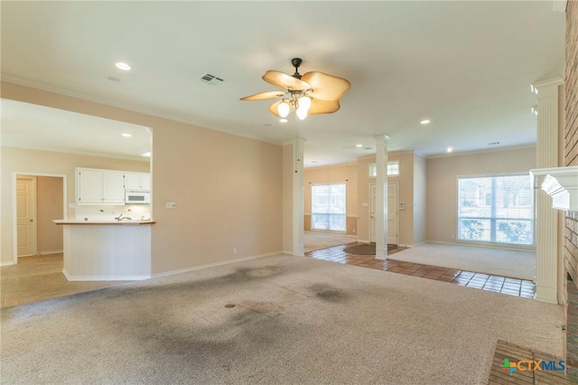 unfurnished living room featuring visible vents, light colored carpet, ornate columns, and ornamental molding