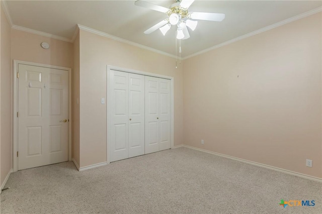 unfurnished bedroom with baseboards, ornamental molding, light carpet, a closet, and a ceiling fan