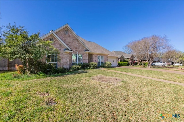 view of front of home featuring a front yard, fence, brick siding, and a garage
