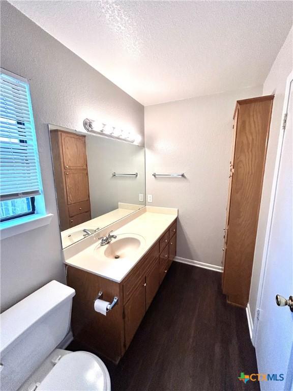 bathroom with toilet, vanity, a textured ceiling, and hardwood / wood-style flooring