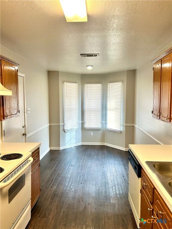 kitchen with a textured ceiling, white appliances, dark hardwood / wood-style floors, and sink