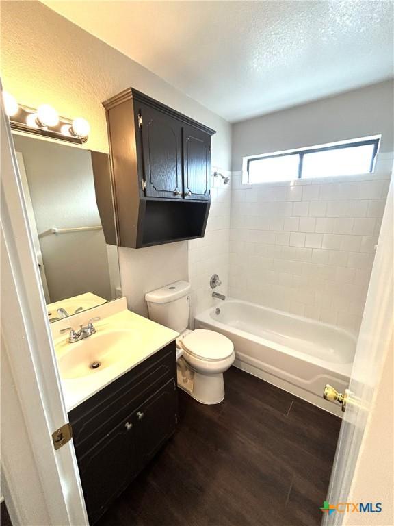 full bathroom with toilet, vanity, wood-type flooring, and tiled shower / bath