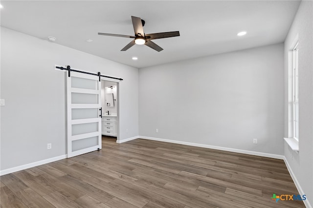 9923 Loma Alta Cir, Converse, TX 78109 - spare room featuring a barn door, ceiling fan, recessed lighting, wood finished floors, and a smoke detector