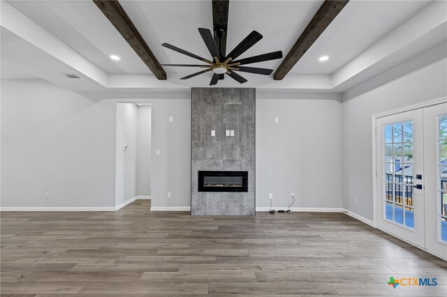 9923 Loma Alta Cir, Converse, TX 78109 - unfurnished living room featuring beamed ceiling, french doors, ceiling fan, wood finished floors, and a tile fireplace