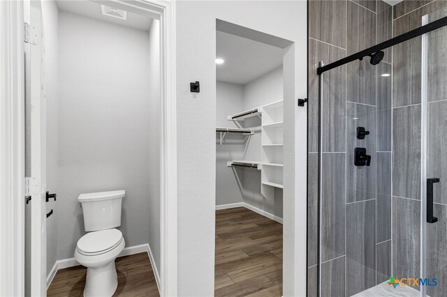 9923 Loma Alta Cir, Converse, TX 78109 - bathroom featuring a stall shower, a spacious closet, and wood finished floors