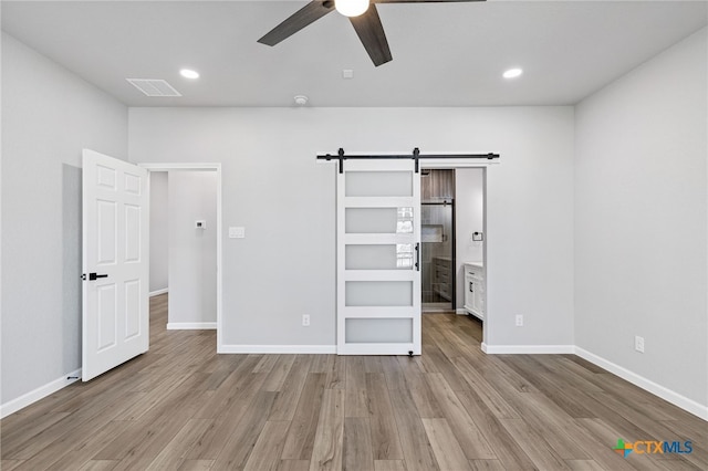 9923 Loma Alta Cir, Converse, TX 78109 - unfurnished bedroom with a barn door, wood finished floors, recessed lighting, ceiling fan, and ensuite bath
