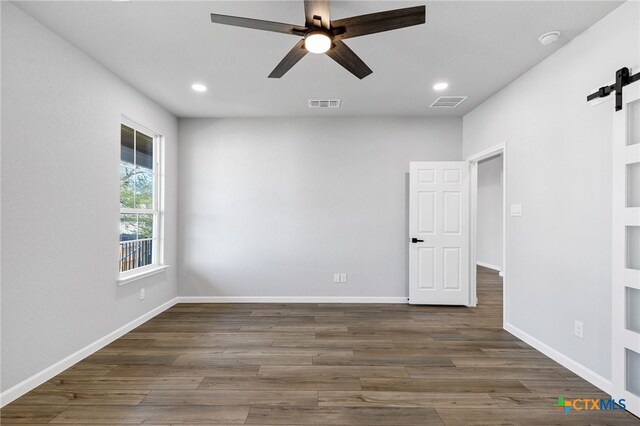 9923 Loma Alta Cir, Converse, TX 78109 - unfurnished room with a barn door, a ceiling fan, a smoke detector, recessed lighting, and wood finished floors