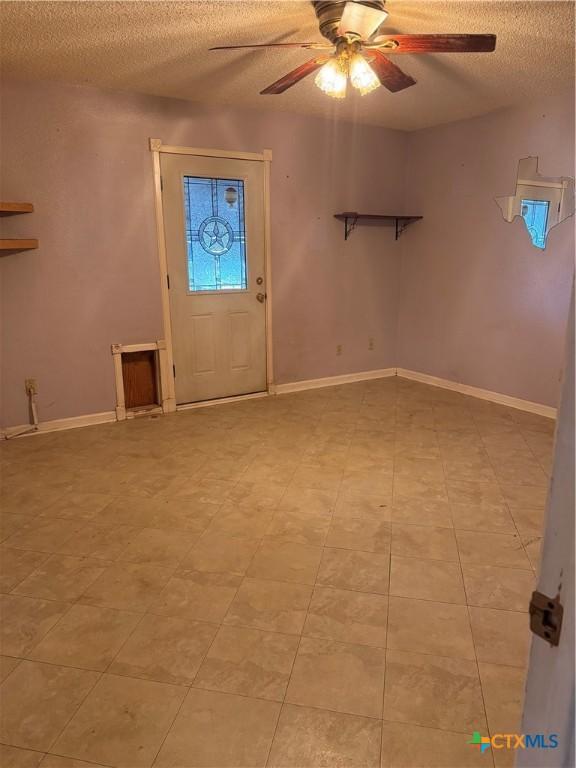 entrance foyer with baseboards, a textured ceiling, and a ceiling fan