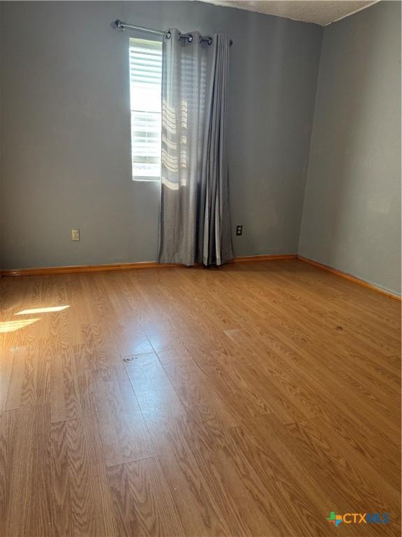 empty room featuring baseboards and light wood-style floors