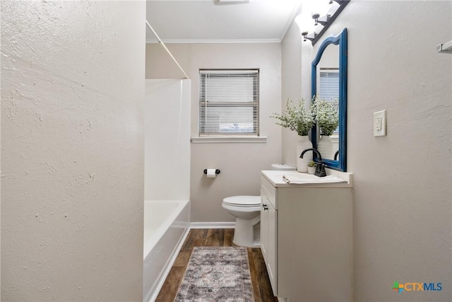 bathroom with baseboards, toilet, wood finished floors,  shower combination, and vanity