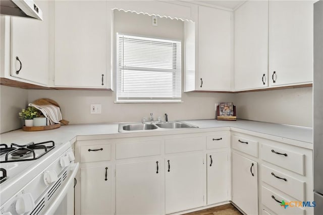 kitchen with white gas stove, light countertops, a sink, and white cabinetry