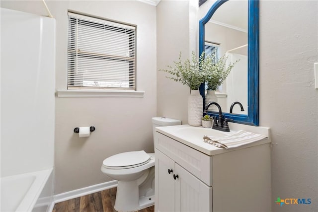 bathroom with a tub to relax in, toilet, wood finished floors, vanity, and baseboards