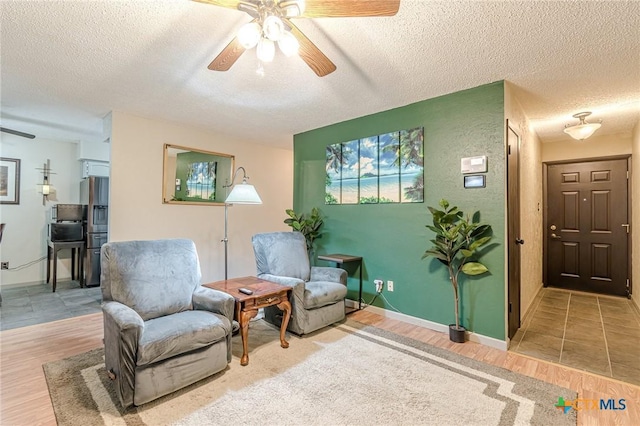 sitting room with a textured ceiling, hardwood / wood-style flooring, and ceiling fan