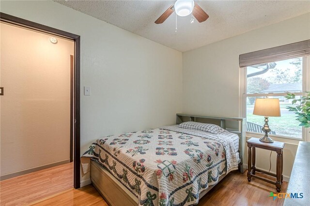 bedroom featuring ceiling fan, hardwood / wood-style floors, and a textured ceiling