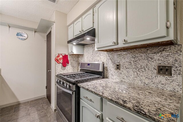 kitchen with stainless steel gas range oven, light stone countertops, a textured ceiling, and tasteful backsplash