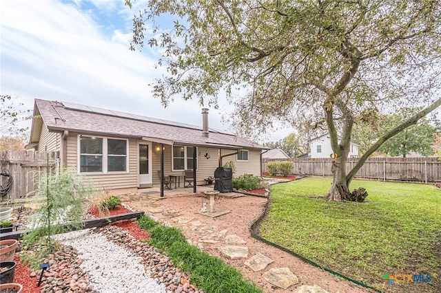 back of property with a lawn, solar panels, and a patio