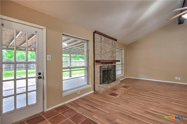 2006 Canyon Creek Dr, Temple, TX 76502 - unfurnished living room featuring a textured ceiling, lofted ceiling, ceiling fan, a fireplace, and wood finished floors