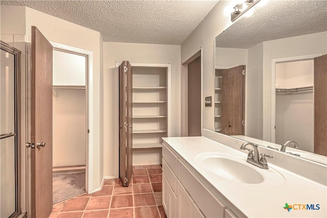 2006 Canyon Creek Dr, Temple, TX 76502 - bathroom featuring a walk in closet, vanity, a stall shower, a textured ceiling, and tile patterned floors