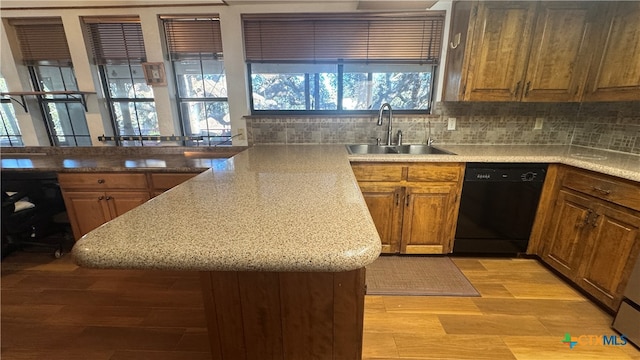 kitchen featuring sink, black dishwasher, tasteful backsplash, light hardwood / wood-style floors, and kitchen peninsula