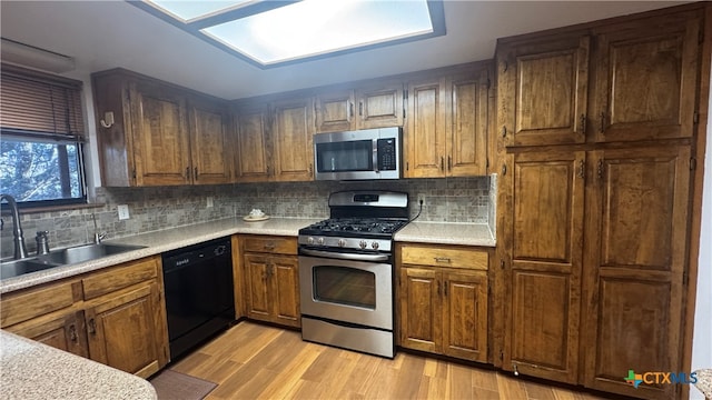 kitchen featuring tasteful backsplash, sink, stainless steel appliances, and light hardwood / wood-style floors