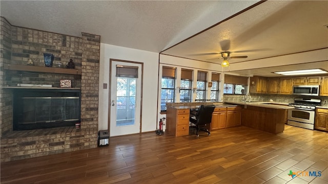 kitchen featuring kitchen peninsula, appliances with stainless steel finishes, dark hardwood / wood-style floors, and a healthy amount of sunlight