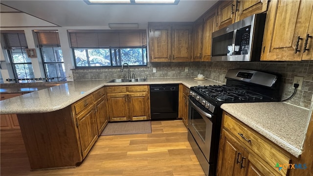 kitchen with sink, light hardwood / wood-style flooring, tasteful backsplash, kitchen peninsula, and stainless steel appliances