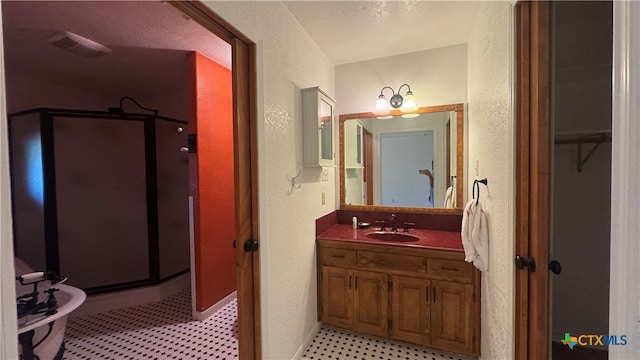 bathroom with a textured ceiling, vanity, and an enclosed shower