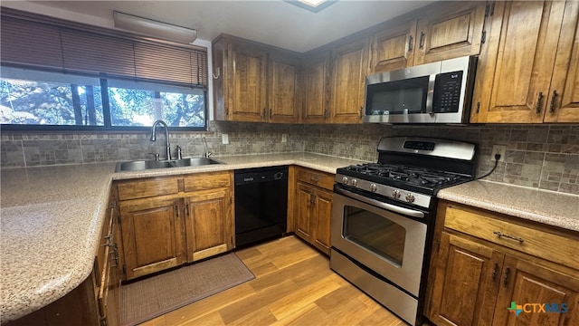 kitchen with tasteful backsplash, sink, light hardwood / wood-style flooring, and appliances with stainless steel finishes