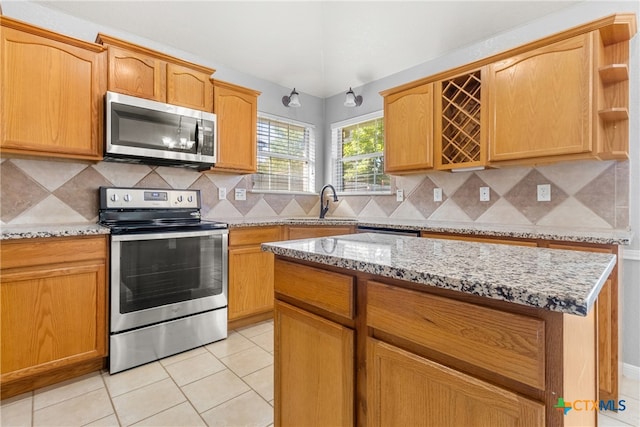 kitchen featuring tasteful backsplash, light stone countertops, light tile patterned floors, and stainless steel appliances