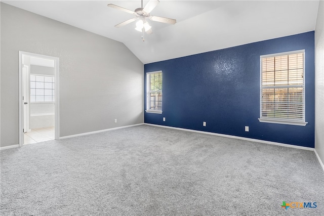 empty room with light colored carpet, vaulted ceiling, and ceiling fan