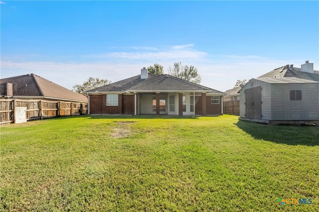 rear view of house featuring a lawn and a storage unit